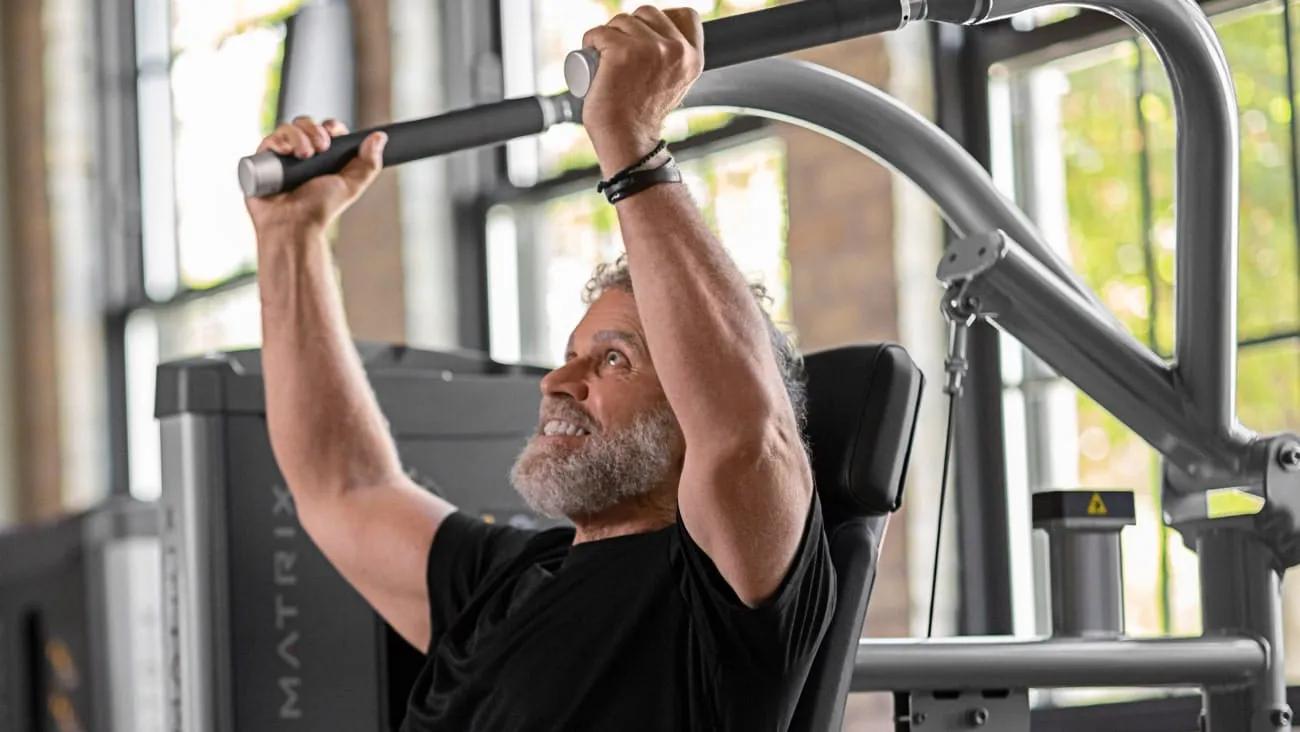 מתאמן מבוגר משתמש במכשיר משיכה עליונה מסדרת Matrix GO
