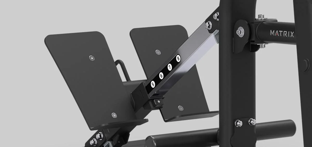 Close-up of the adjustable footplate mechanism on a Matrix Fitness leg press machine in Matte Black, showing numbered positions for customization.
